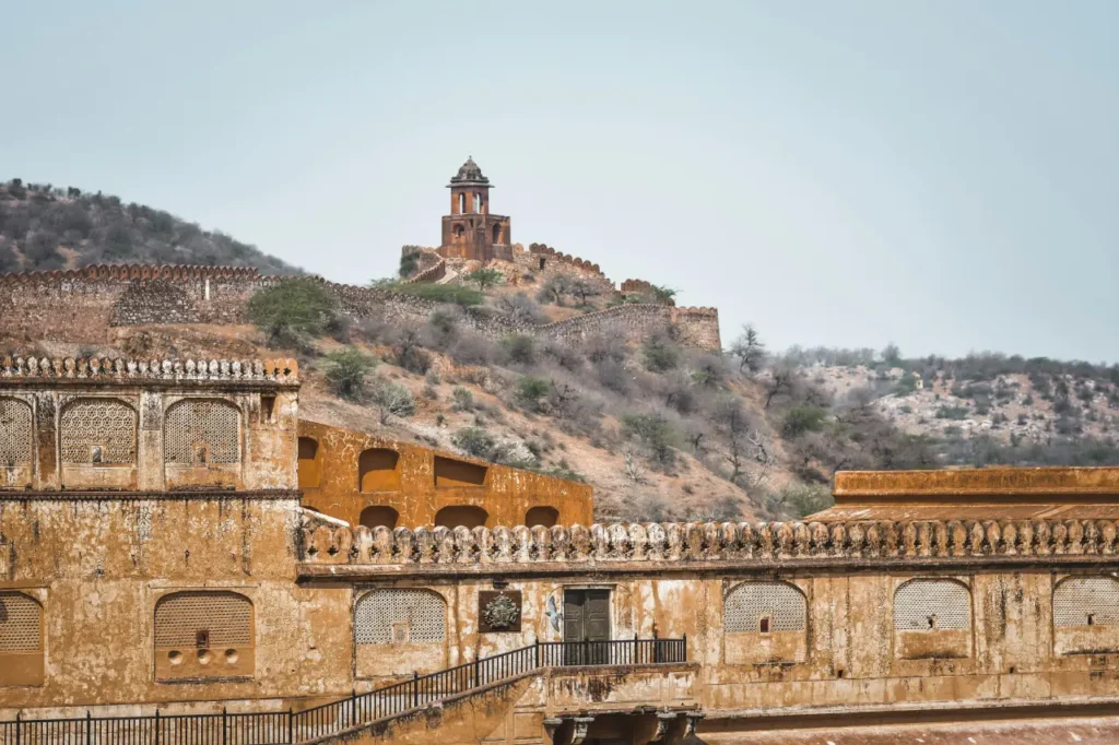 Historic view of Amber Fort with Jaigarh Fort’s hilltop watchtower and connecting fort walls in Jaipur, Rajasthan.